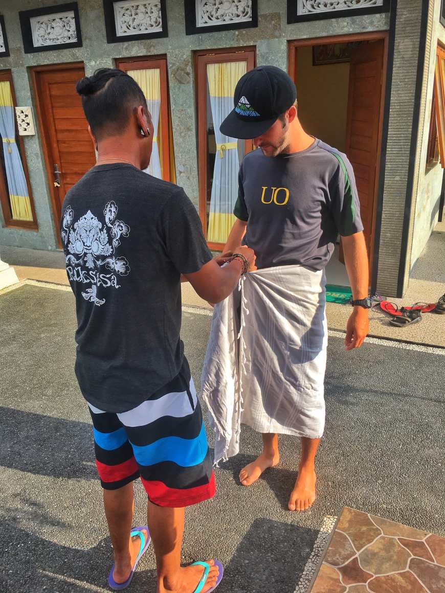Remy teaching TJ how to tie his sarong in the traditional Balinese way before we going to Tirta Empul